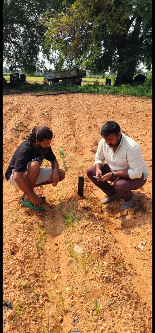 Two field operators checking Soilo Essence and a mobile phone in prepared farmland