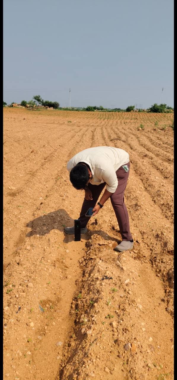 Field operator checking a mobile phone beside Soilo Essence during soil testing