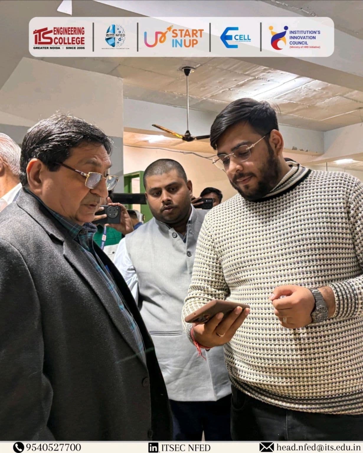 Participants reviewing a mobile device in the institutional photo supplied with the NewGen Demo Day update